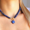 Blue beaded necklace with a unique pendant on a person wearing a white top.