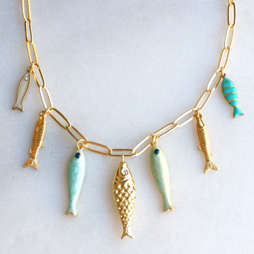 Necklace with gold and turquoise fish pendants on a light gray background