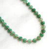 Green beaded necklace on a white background