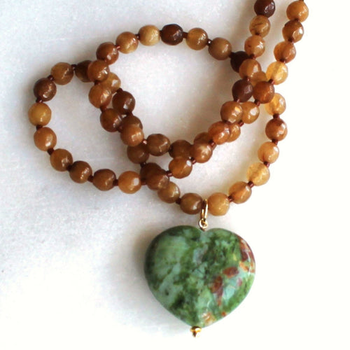 Necklace with brown beads and a green heart-shaped pendant on a white background