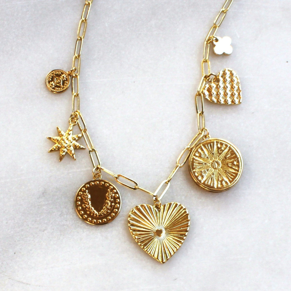 Gold necklace with various pendants on a white background