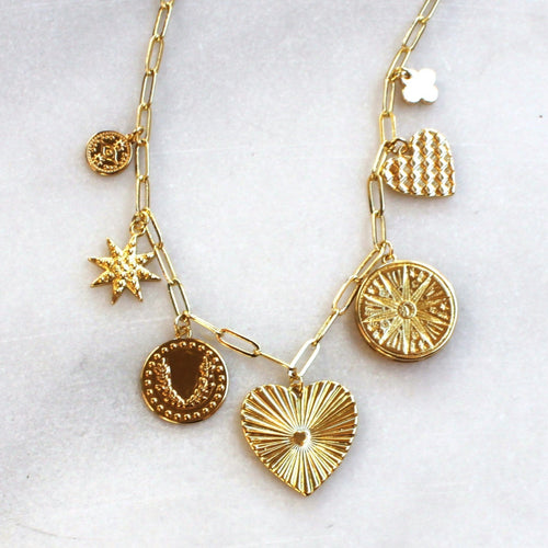 Gold necklace with various pendants on a white background