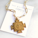Gold necklace with a cross pendant on a branded card