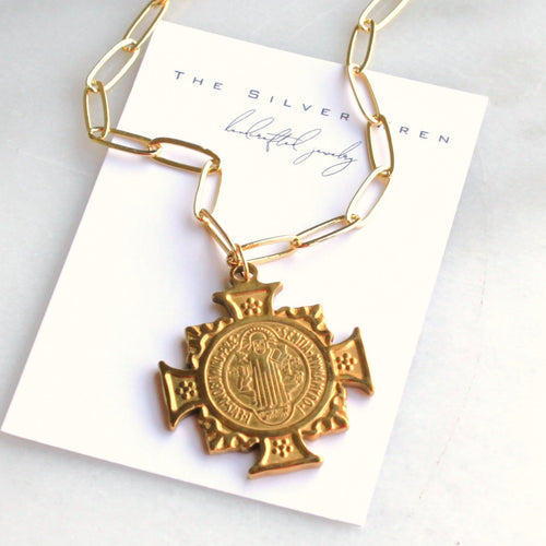 Gold necklace with a cross pendant on a branded card