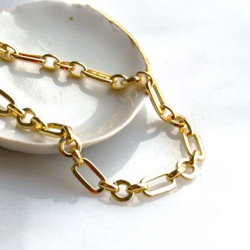 Gold chain necklace on a white dish with a light background