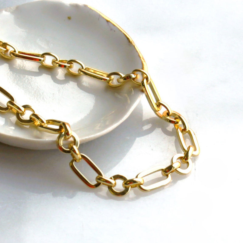 Gold chain necklace on a white dish with a light background