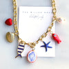 Gold necklace with colorful charms on a white card, featuring 'The Silver Wren' brand.