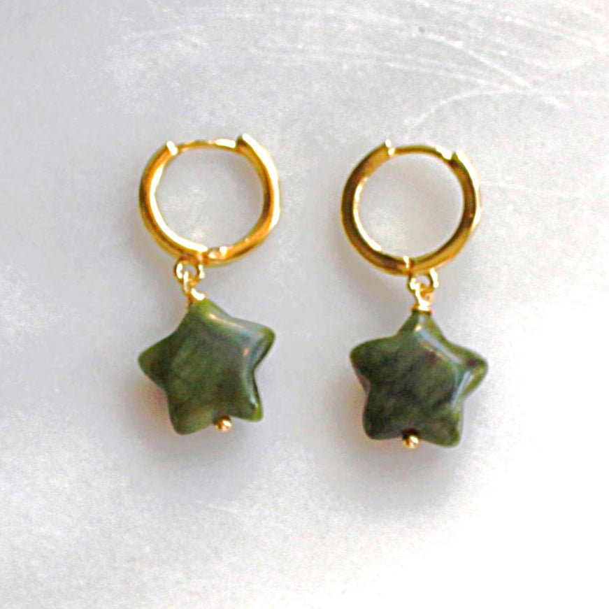 Gold hoop earrings with green star-shaped charms on a white background