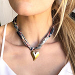 Woman wearing a colorful necklace with a heart pendant.