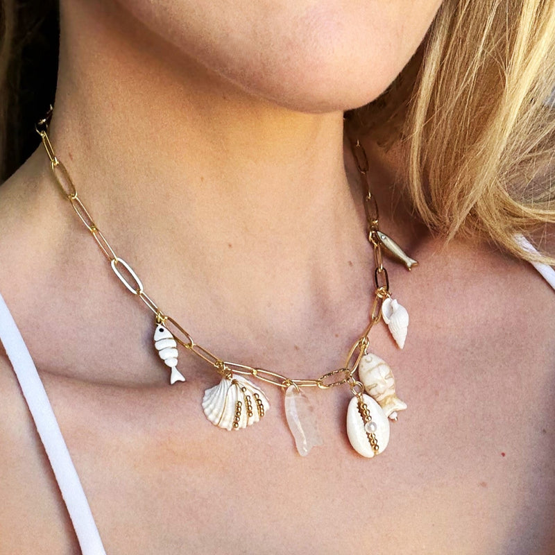 Necklace with shell pendants worn by a person in a white top.