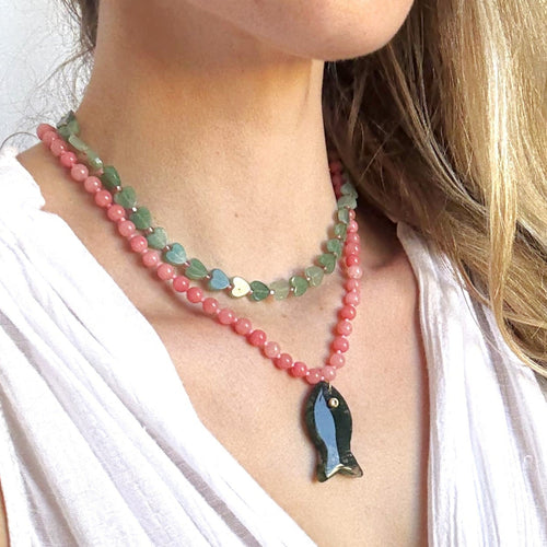 Close-up of a woman wearing a colorful beaded necklace with a fish pendant.