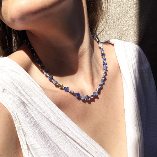 Necklace with blue beads worn by a person in a white top.