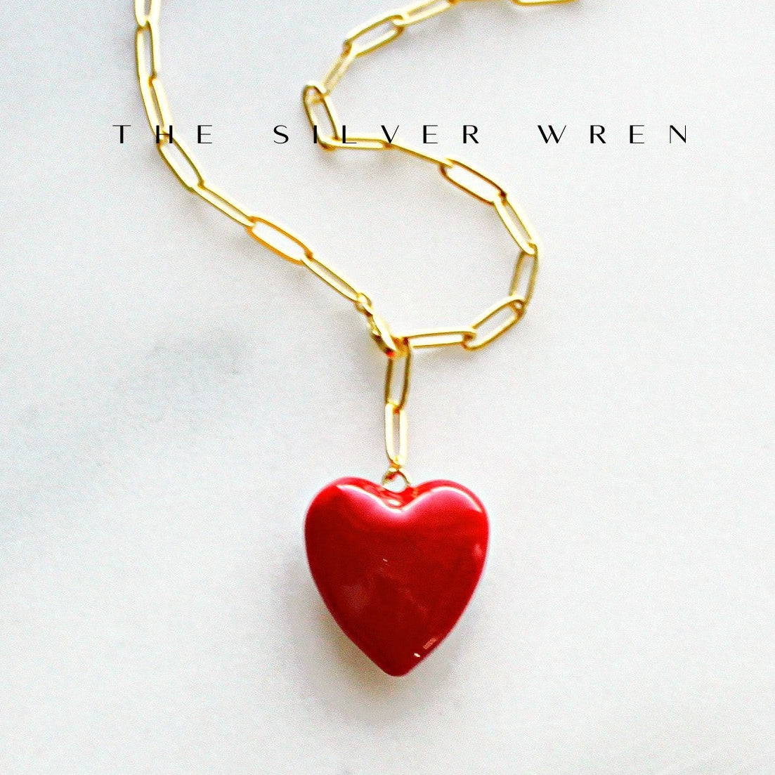 Gold chain necklace with a red heart pendant on a white background, branded 'The Silver Wren'.