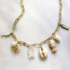 Gold necklace with shell and fish charms on a light background